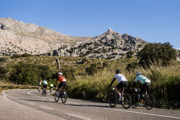 A group of cyclists during the Mallorca 312 event on a sunny day, with blue skies