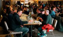 A group of people gathered around a table filled with food and drinks at a hotel.