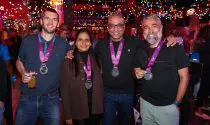 A group of runners, posing for for a photo at a Sports Tours International marathon after-party, with their marathon medals.