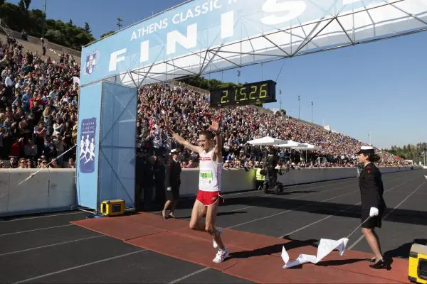 A runner waving his hands as he crosses the marathon finish line