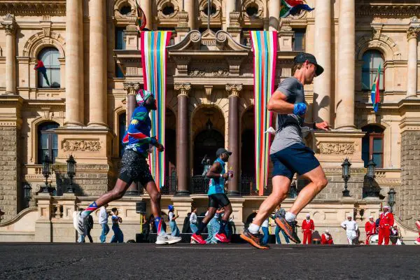 Sanlam Cape Town Marathon runners passing by the Cape Town City Hall, showcasing its impressive architecture.
