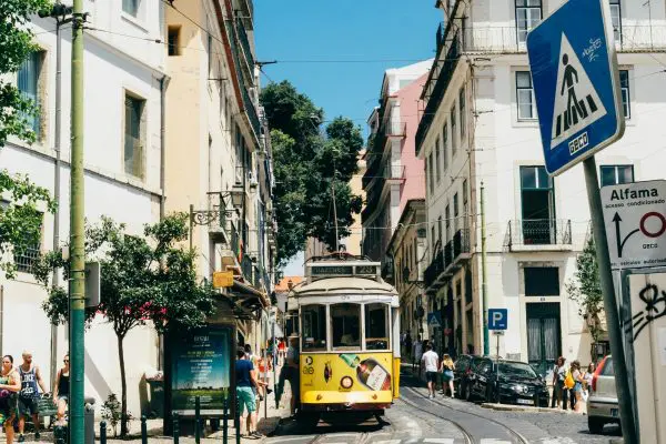 A street in Lisbon featuring a yellow tram and colourful buildings