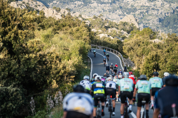 A group of cyclists during the Mallorca 312 event on a sunny day, with blue skies