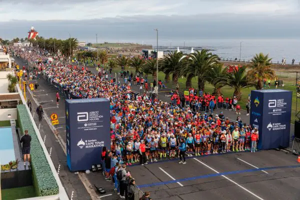 Large group of runners in the Sanlam Cape Town Marathon at the start line on the coast, with the sea in the background with grey skies