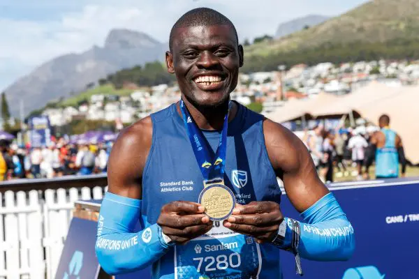 Runner at the Sanlam Cape Town Marathon holding his gold finishing medal with both hands and smiling