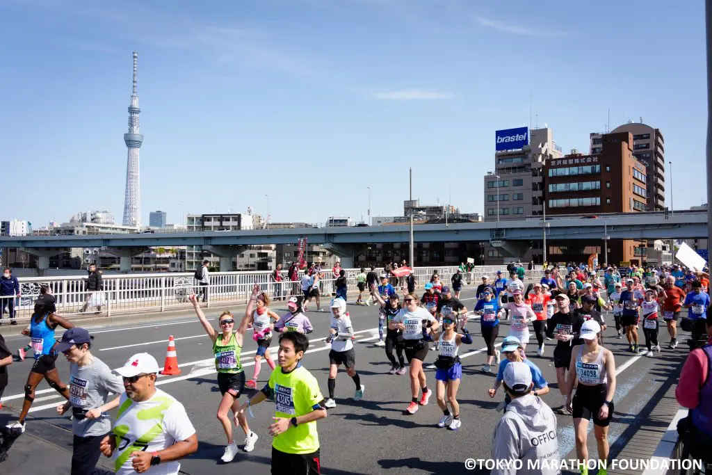 Runners at the Tokyo Marathon running on the road with Tokyo Skytree in the background